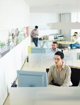 Contemporary businesswoman computing by her workplace in open space office