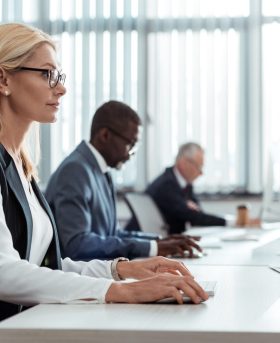 selective focus of concentrated blonde businesswoman working near multicultural coworkers