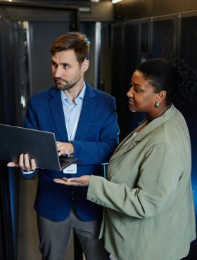 High angle view at two people in server room using laptop and checking data security